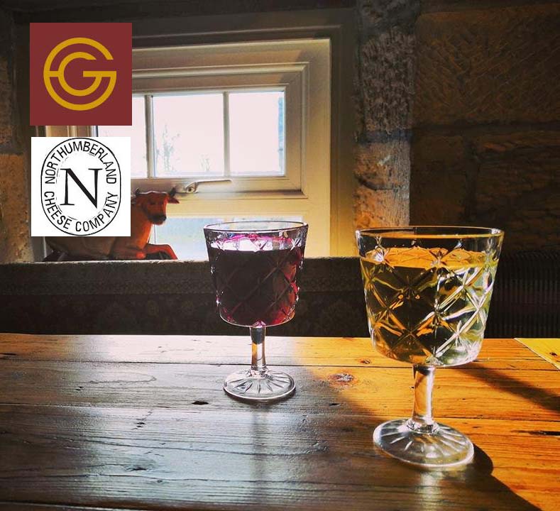 Glasses of red and white wine on a wooden table by a window, with the Grape and Grain and Northumberland Cheese Company logos