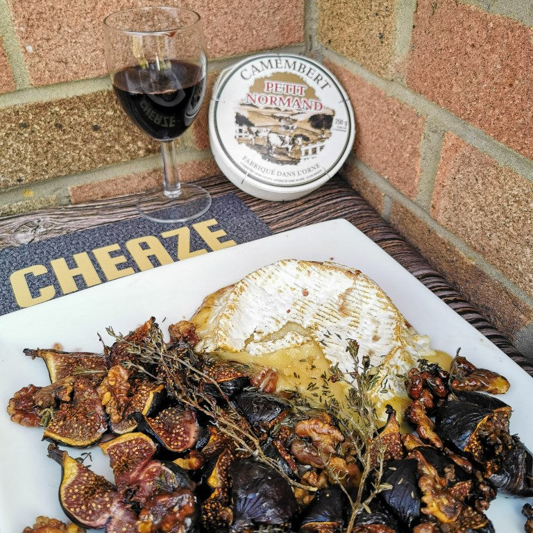 Baked Petit Normand Camembert with roasted figs, walnuts and thyme, the cheese box and a glass of red wine behind