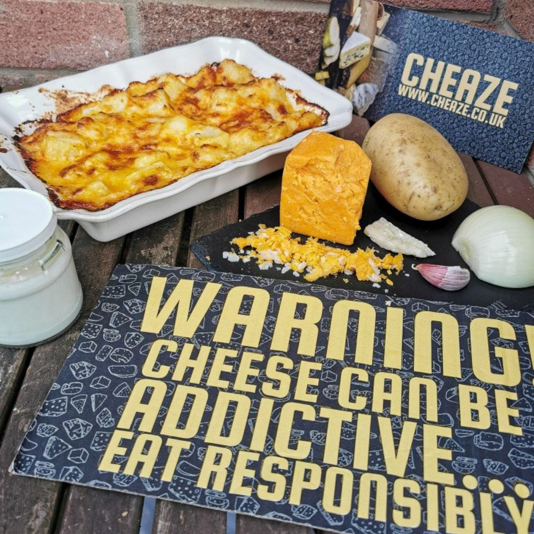 Red Fox chunky potato gratin in a white dish with a wedge of Red Fox, a potato, onion and garlic, and Cheaze signs