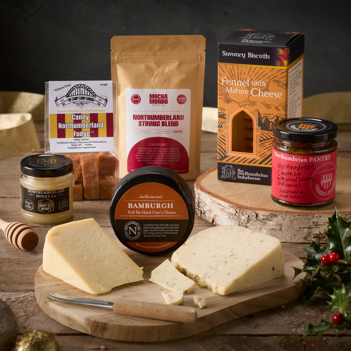 Northumbrian Christmas hamper: a Bamburgh truckle and cheese wedges on a board with Northumberland honey, Canny Northumberland fudge, Mocha Mondo coffee, fennel and mature cheese biscuits and spiced plum chutney, beside holly