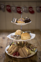 Cheese Loft Café afternoon tea stand with cheese sandwiches, scones and cakes, festive stocking bunting behind