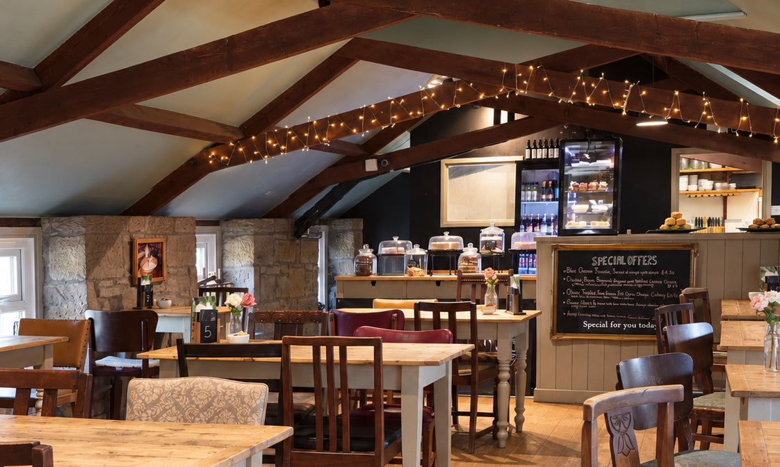 The Cheese Loft Café, with fairy lights on its timber beams, wooden tables and chairs, and the cake counter at the back