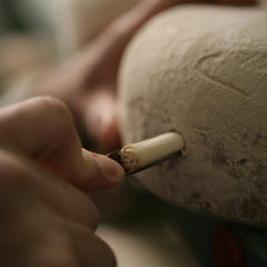 A cheese iron drawing a core sample from a natural-rind cheese to check how it is maturing