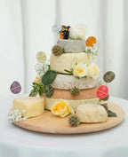 Tiered cheese wedding cake with name flags such as Nettle and Chilli, cream and yellow roses and toy bride and groom figures