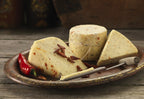 Chilli Cheese wedges and a small truckle flecked with red chilli, on a rustic plate with fresh and dried chillies
