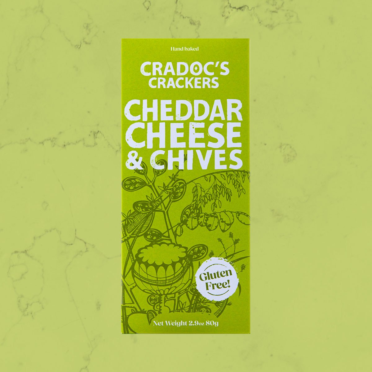 Green 80g box of Cradoc's Gluten Free Cheddar & Chives Crackers on a matching green marble background
