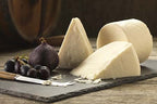 Wedges and a small round of white Elsdon goats' cheese on a slate with a fresh fig, black grapes and a cheese knife