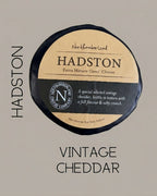 Black-waxed Hadston truckle on a grey background, captioned Hadston Vintage Cheddar