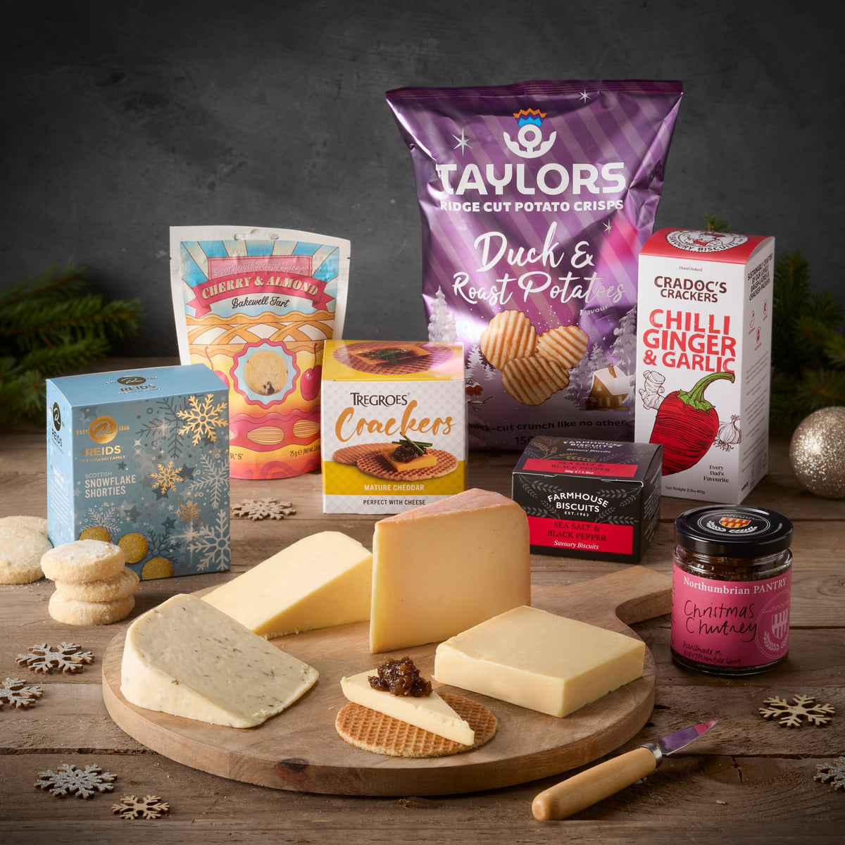 Merry Cheesemas Box: four cheeses on a round board with Taylors crisps, a Bakewell tart, shortbread, crackers and Christmas chutney