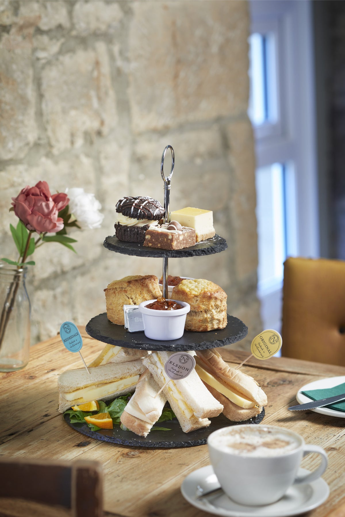 Afternoon tea on a three-tier slate stand: cheese sandwiches flagged Redesdale, Elsdon and Original, scones and cakes