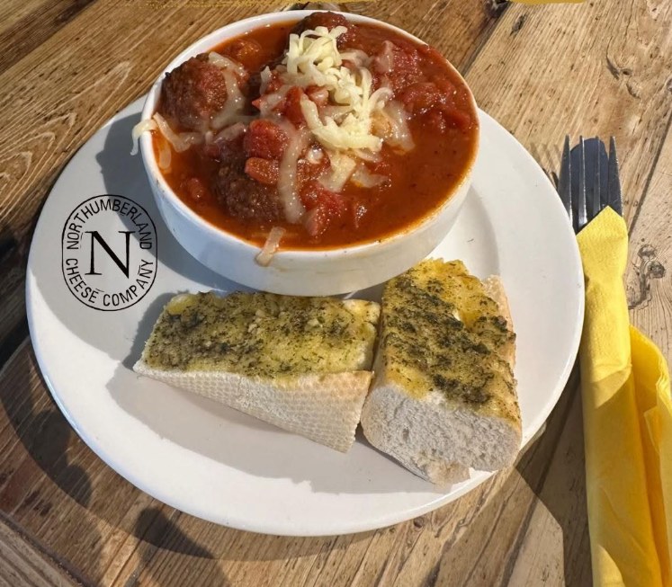 Meatballs in tomato sauce topped with grated cheese, served with two slices of garlic bread at the Cheese Loft Café
