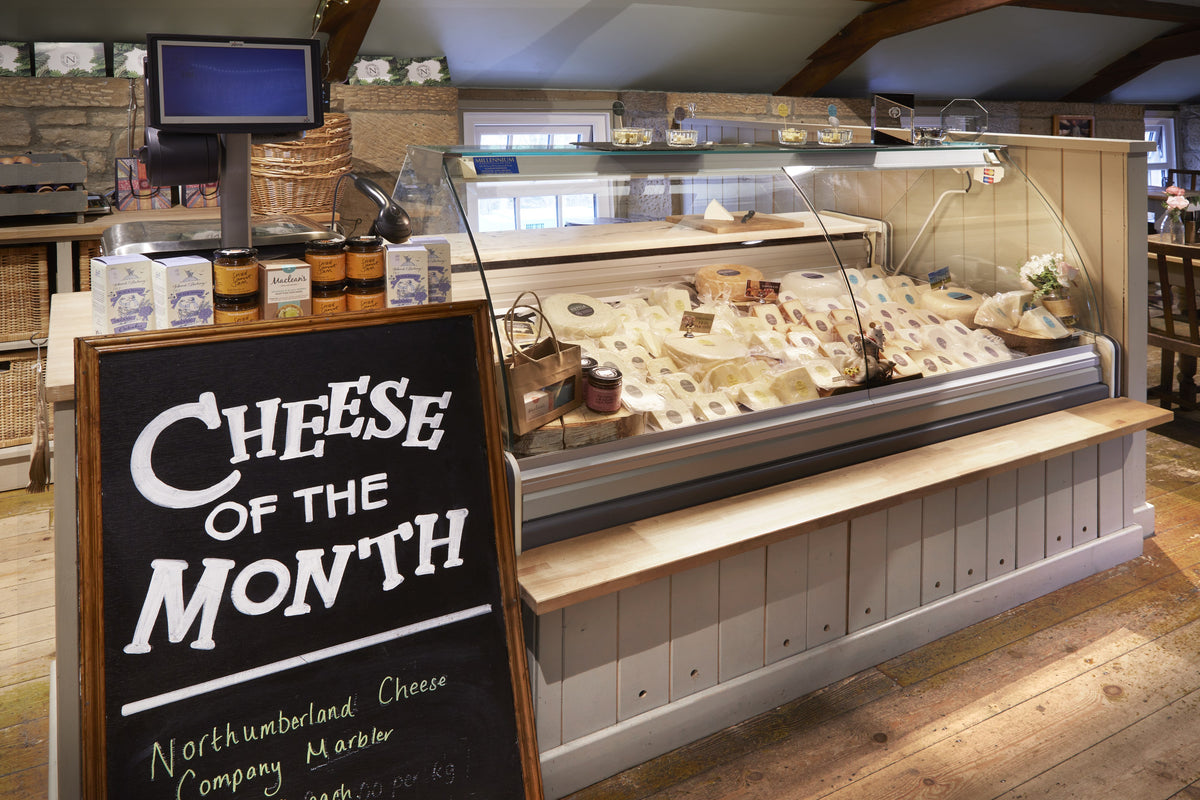 The deli counter in the Northumberland Cheese Company shop with the Cheese of the Month board
