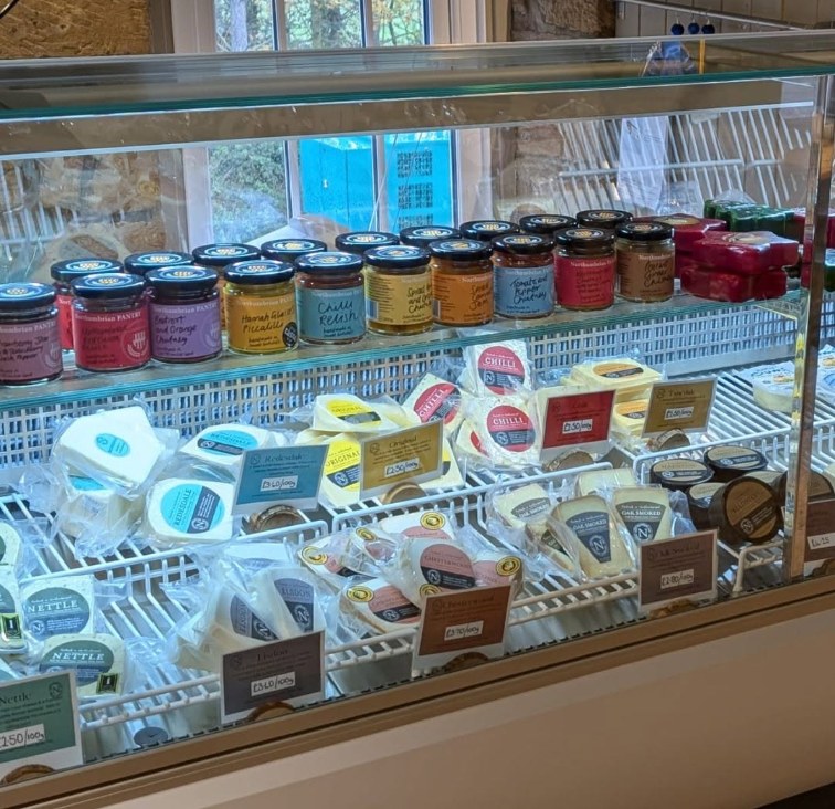 The Cheese Loft Shop's chilled cabinet: jars of chutney and relish above wrapped Nettle, Chilli, Oak Smoked and Original cheeses