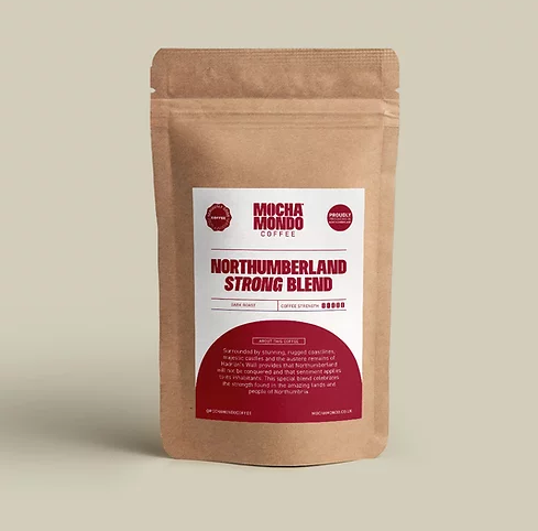 Kraft pouch of Mocha Mondo Northumberland Strong Blend coffee with a red and white label, set on a plain beige background