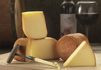Oak Smoked Cheese truckles with bronzed rinds and pale wedges, a cheese iron, and a bottle and glass of red wine