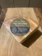 Vacuum-packed wedge of Oak Smoked Cheese with its bronzed rind and olive label, on a rustic wooden board