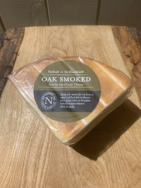 Vacuum-packed wedge of Oak Smoked Cheese with its bronzed rind and olive label, on a rustic wooden board