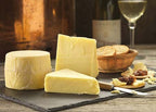Original Cheese truckle and wedges on a slate with crackers, chutney and a glass of white wine