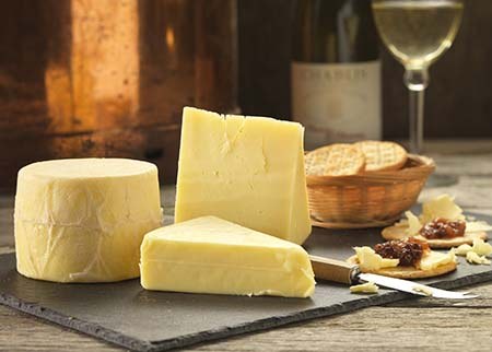 Original Cheese truckle and wedges on a slate with crackers, chutney and a glass of white wine