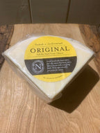 Vacuum-packed wedge of Original Cheese with its yellow label, standing on a rustic wooden board